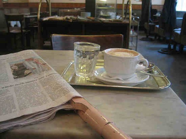 Una tazza di caff, un giornale e un bicchiere d'acqua